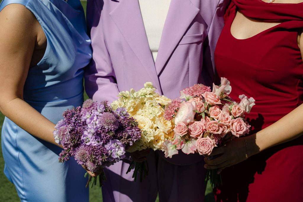 Spring colored bridesmaids bouquets featuring roses, ranunculus, stalk, and sweet pea