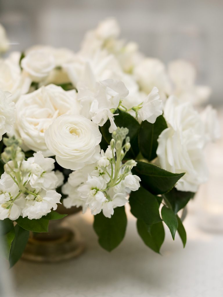 A classic meets modern, white wedding at the Austin Country Club. This wedding reception features luxe white wisteria dripping from the ceiling, a garden style design aesthetic, lots of candles, Stage floral, and a head table overhead installation flanking the dance floor. In Austin Texas