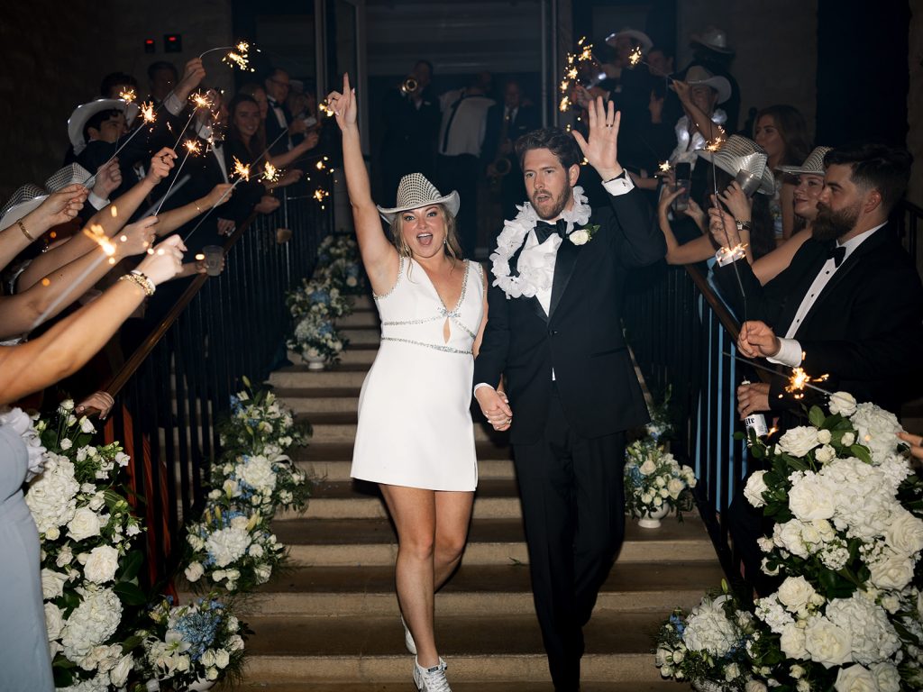 A classic meets modern, white wedding at the Austin Country Club. This wedding reception features luxe white wisteria dripping from the ceiling, a garden style design aesthetic, lots of candles, Stage floral, and a head table overhead installation flanking the dance floor. In Austin Texas