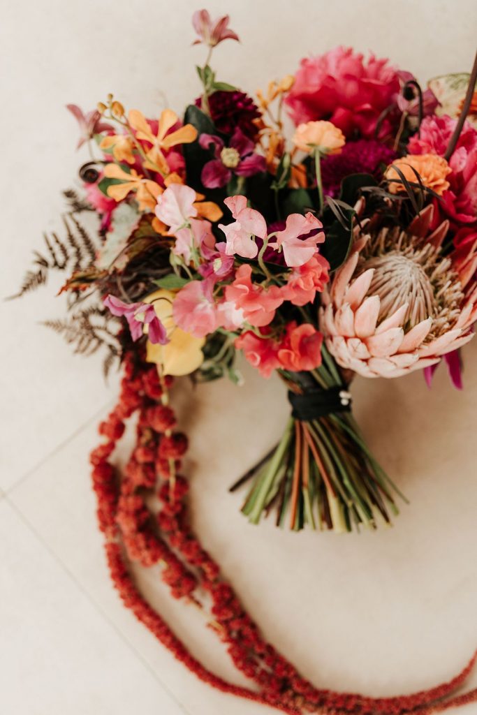 A bridal bouquet with unique blooms like a king protea, amaranthus, sweet peas, and orchids.